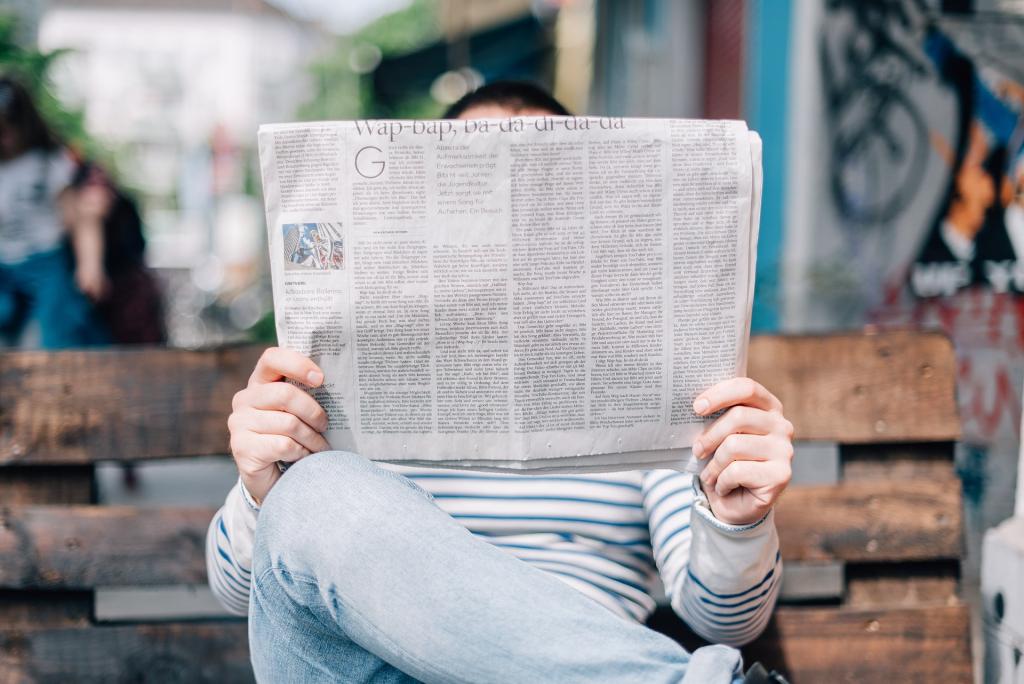 Homme sur un banc lisant un journal