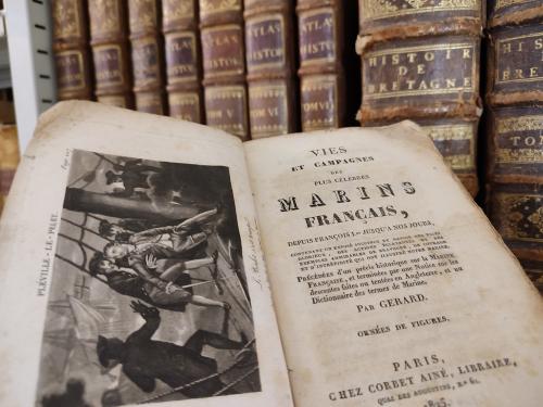 Livre "Marins Francais" ouvert devant une étagère
